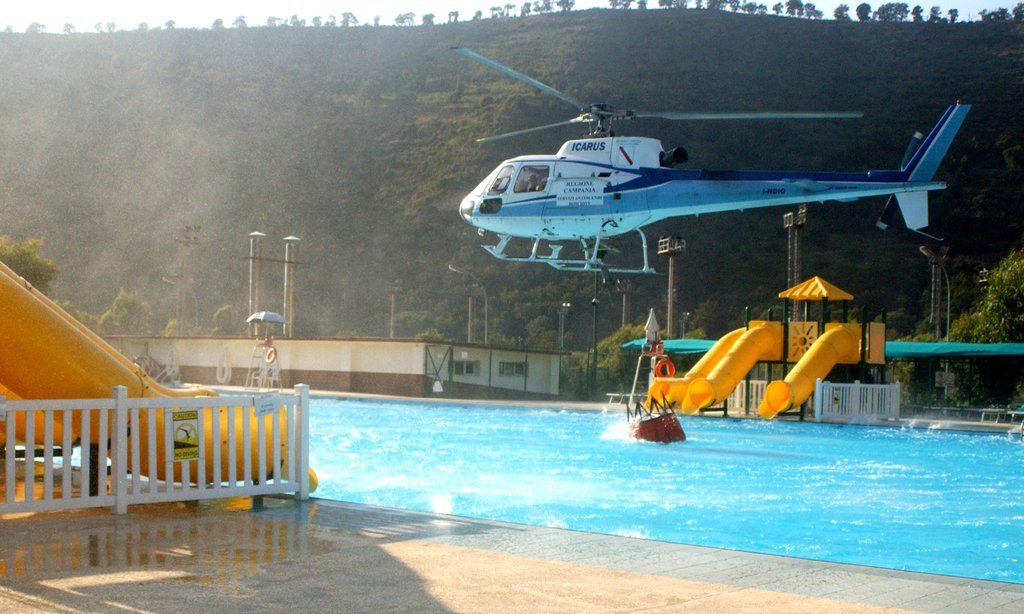 040901-N-1362W-008 Naples, Italy (Sept. 1, 2004) - An Italian firefighting helicopter loads-up its 125-gallon bag with water from the Carney Park public swimming pool aboard Naval Support Activity (NSA), Naples, while assisting local authorities with fighting local wild fires. The Italian firefighters contacted the NSA Fire Department requesting use the pool, which help reduce the turn-around time for the helicopters from four to five minutes to less than 60 seconds. U.S. Navy photo by Journalist 1st Class Stephen Woolverton (RELEASED)